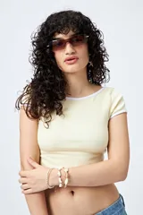 Top corto de punto acanalado color rosa, con silueta ajustada, escote redondo y ribetes blancos en cuello y mangas.