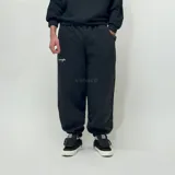 Pantalón de jogging negro de felpa con corte oversize y logo estampado en blanco en el muslo izquierdo.