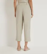Pantalón zanahoria color beige de liocel, con pliegues delanteros, bolsillos laterales y cierre con cremallera y botón.