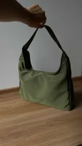 Cartera tipo baguette negra de lona semi impermeable con cierre metálico y forrería de gross con bolsillo interno.