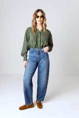 Camisa verde militar de manga larga con cuello camisero, cierre frontal con botones, dos bolsillos con solapa en el pecho y puños abotonados.