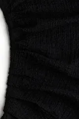 Vestido corto negro sin mangas en punto efecto arrugado. Modelo entallado con cuello elevado corto y pliegues en un hombro y en un lado de la cintura para crear un efecto drapeado suave.