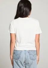 Remera color crema de corte cropped, con cuello redondo y mangas cortas. Estampado frontal con el logo de Coca-Cola, un jinete a caballo y la frase "The Wild West The Best" en color marrón.