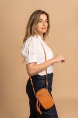 Bandolera compacta de símil cuero color rojo, con correa regulable y desmontable. Posee apertura superior, bolsillo frontal con cierre y bolsillo trasero abierto.