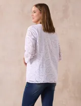Blusa blanca de broderie con cuello a la base y escote en V. Apliques de brillos y piedras nacar en la parte delantera.