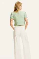 Top corto verde agua en punto arrugado con escote en V y doble cordón de ajuste abajo del busto que se enlaza adelante. Mangas cortas con elástico revestido y ribete sobrehilado.