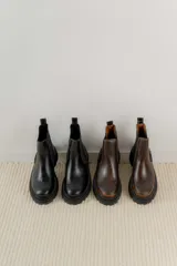 Bota Chelsea de cuero negro con elástico lateral y suela track.