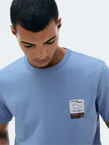 Camiseta de manga corta color ladrillo con cuello redondo y estampa cuadrada con paisaje de montañas en el pecho.