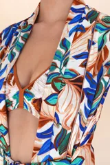 Cover up largo sin mangas con estampado de hojas en tonos azul, marrón y verde. Presenta un diseño fluido con escote en V profundo y un lazo ajustable en la cintura para definir la silueta.