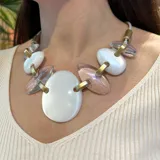 Collar corto con cordón marrón y piezas ovaladas de resina color marrón y blanco con detalles dorados, unidas por eslabones dorados. Diseño italiano de Fahoma.