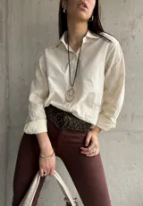 Camisa beige de manga larga con bordado floral en las mangas y cuello clásico.