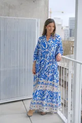 Vestido largo de corte holgado con estampado floral en tonos azul y blanco. Tiene cuello en V, mangas largas y falda con volantes.