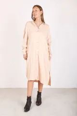 Vestido camisero color beige de manga larga, confeccionado en rayon twill, con cuello camisero y cierre frontal con botones.