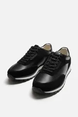 Zapatilla deportiva negra con detalles en piel y acabado serraje.