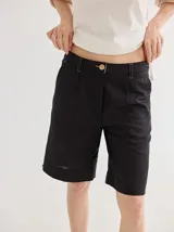 Short negro de lino, tiro medio y corte a la rodilla. Presenta botón de madera y costuras a contratono.