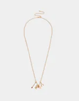 Collar dorado con cadena de eslabones y dijes colgantes: fósforo con cabeza roja, naipe con corazón y dado esmaltado rosa.