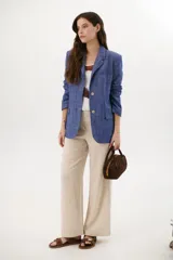 Pantalón de lino azul de corte palazzo con botón decorativo en la cintura.