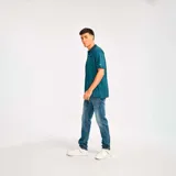 Remera tipo polo color petróleo con cuello de punto acanalado, puños de manga de punto plano y parche de silicona con el logo de Cat en el lado izquierdo del pecho.