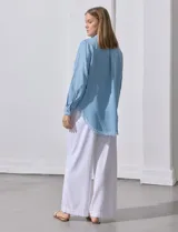 Camisa de jean celeste con flecos en el ruedo, de mangas largas y corte recto.