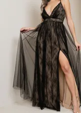 Vestido largo de fiesta con escote profundo en V, confeccionado en encaje negro sobre una base color piel y tul negro. Tiene breteles finos y falda con tajo alto.