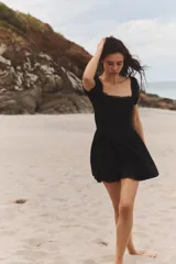 Vestido corto negro de popelín con escote cuadrado, mangas cortas abullonadas, bolsillos laterales ocultos y detalle de encaje a tono.