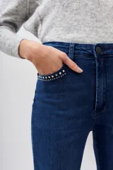 Jean de corte slim, tiro medio, confeccionado en denim azul con lavado localizado y detalles de hot fix en los bolsillos delanteros.