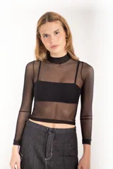 Top de tul negro traslúcido, con cuello alto y mangas largas. Incluye top bandeau negro debajo.