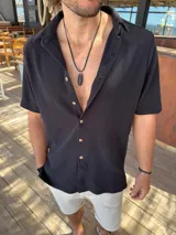 Camisa negra de algodón con textura waffle, corte clásico, cuello americano y botones color madera.