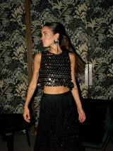 Top corto negro sin mangas, con lentejuelas plateadas y doradas.