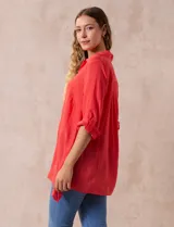 Camisa color beige claro, de corte recto y mangas 3/4 con botón para sujetar.