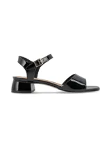 Sandalias negras de charol con pulsera al tobillo y hebilla dorada.