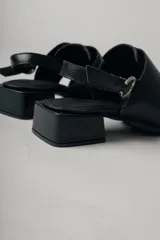 Sandalias negras de cuero con diseño de tiras entretejidas, puntera cuadrada, tira trasera con hebilla ajustable y tacón bajo cuadrado.