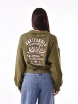 Buzo deportivo color verde oliva con cuello polo y puños ajustados.
