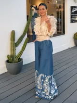 Pantalón palazzo de jeans azul con bordado floral blanco en el ruedo y cintura alta con cinturón ancho color beige con tachas.