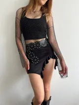 Minifalda negra con volados en el ruedo y cintura alta con cinturón de cuero con apliques metálicos.
