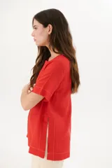 Blusa manga corta color rojo con cortes laterales y abertura abotonada en la espalda. Los pespuntes a contratono resaltan el escote y los cortes.