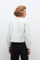 Chaqueta color blanco con bordado floral, cuello camisero, cierre frontal con botones y mangas largas.