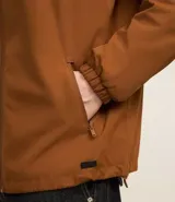 Campera rompevientos color verde oliva, con capucha ajustable con cordón, cierre frontal con cremallera, bolsillos laterales con cremallera y puños elásticos.