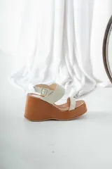 Sandalias de cuero color hueso con plataforma de madera color marrón.