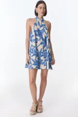 Vestido corto con estampado floral en tonos rojo y beige, cuello halter y corte evasé.