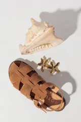 Sandalias bajas de cuero marrón con tiras entrecruzadas y hebilla dorada.