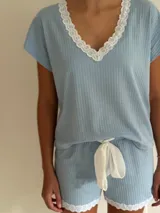 Pijama de algodón celeste con remera de escote en V con puntilla blanca y short con elástico en la cintura, lazo y terminación con puntilla.
