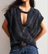 Remera negra con cuello redondo y abertura en forma de gota en el escote. Decorada con apliques metálicos en forma de V.