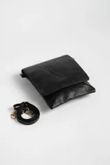 Bandolera negra de cuero sintético con correa larga regulable y cierre con solapa.