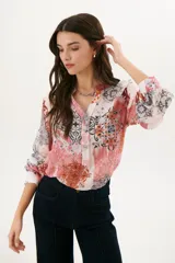 Camisa estampada color rosa con cuello mao, mangas largas abullonadas y cierre frontal con botones.