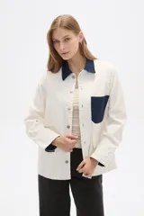 Chaqueta color crudo de algodón con cuello camisero y detalles en denim azul en cuello, bolsillo y puños.