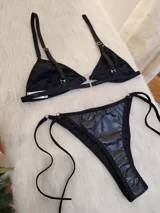 Conjunto de bikini negro de cuerina, con corpiño triangular y bombacha colaless con tiras laterales ajustables.