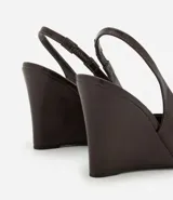 Zapato de tacón tipo anabela (cuña) color marrón oscuro, con punta fina y diseño slingback con tira elástica en el talón. Confeccionado en poliuretano con acabado liso.