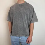 Remera gris con efecto gastado, corte boxy y estampado en la espalda con una estrella azul y texto "White Noise".