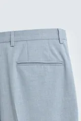 Pantalón de vestir celeste claro, corte slim fit, con bolsillos laterales y traseros de doble vivo con botón. Cierre frontal con cremallera y botón.